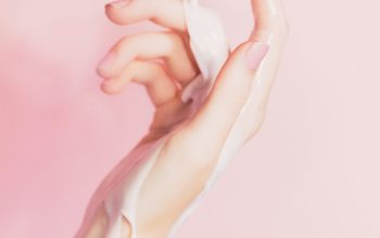 Wallpaper A Woman’s Hand Holding a Lotion Bottle