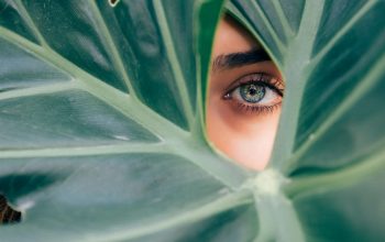 Wallpaper Woman Peeking Over Green Leaf Plant