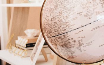 Wallpaper White and Black Desk Globe on Top of Magazines