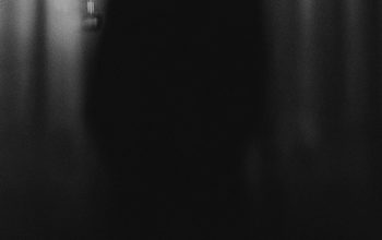 Wallpaper A Person Standing in Front of a Curtain in the Dark