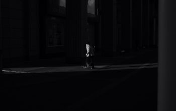 Wallpaper A Person Walking Down a Dark Street at Night