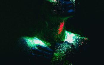 Wallpaper A Woman Covered in Colored Powder in the Dark