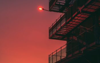 Wallpaper Airplane Flying Over Building at Sunset