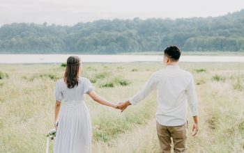 Wallpaper A Man and Woman Holding Hands Walking Through Tall Grass