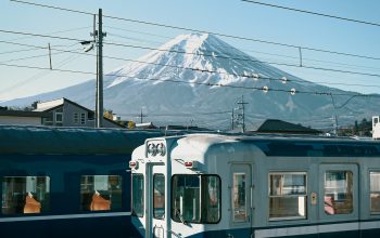 Wallpaper A Blue and White Train Traveling Past a Snow-Covered Mountain