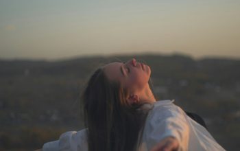 Wallpaper A Woman Standing in a Field with Outstretched Arms