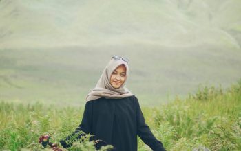 Wallpaper A Woman in a Hijab Walking Through Tall Grass