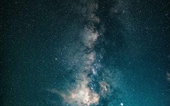 Wallpaper A Person Standing on Top of a Hill Under a Night Sky