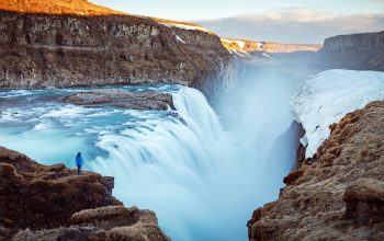 Wallpaper Person Standing on Cliff near Large Waterfalls