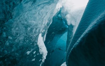 Wallpaper A Large Ice Cave with Water Coming Out of It