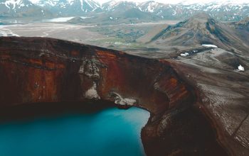 Wallpaper Body of Water Near Mountain with Distant Snow-Capped Peak