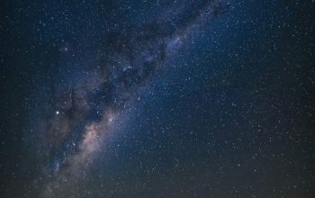 Wallpaper A Man Standing on a Beach Under a Night Sky