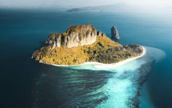 Wallpaper Brown and Green Mountain Beside Blue Sea Under White Clouds and Blue Sky