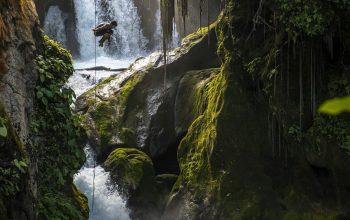 Wallpaper Waterfalls Amidst Mossy Rocks