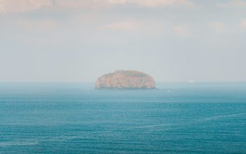 Wallpaper Brown Rock Formation on Blue Sea Under White Clouds