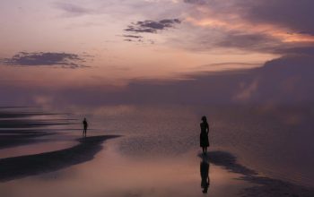 Wallpaper Silhouette of Person on Seashore at Sunset