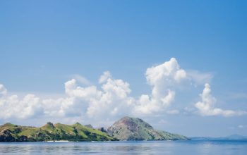 Wallpaper Green Island on Blue Sea Under Blue Sky and White Clouds