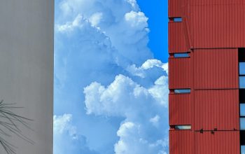 Wallpaper A Red Building and a White Building Against a Blue Sky