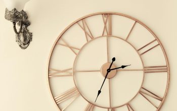 Wallpaper A Clock on a Wall Next to a Wall Sconce