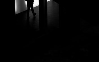 Wallpaper A Man Standing in a Dark Room Next to a Wall
