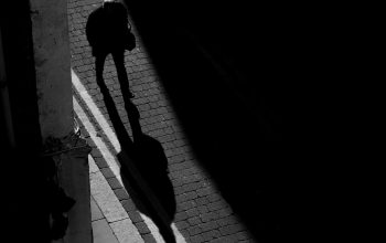 Wallpaper A Shadow of a Person Walking Down a Street