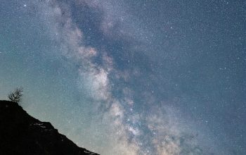 Wallpaper A Mountain with a Starry Sky Above