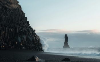 Wallpaper A Rocky Beach with a Large Rock Formation