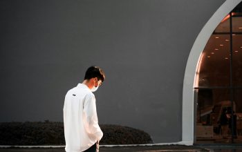 Wallpaper A Man in a White Shirt Walking Down the Street