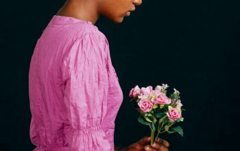 Wallpaper A Woman in a Pink Dress Holding a Bouquet of Flowers