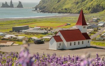Wallpaper A Red and White Building with a Red Roof Surrounded by Purple Flowers