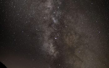 Wallpaper A Starry Night Sky Over a Mountain Range
