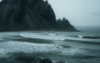 Wallpaper A Rocky Beach with Waves Crashing Against It