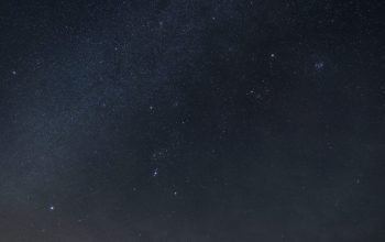 Wallpaper A Train Traveling Over a Bridge Under a Night Sky