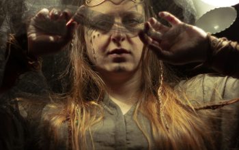 Wallpaper A Woman Holding Her Hair in Front of a Mirror