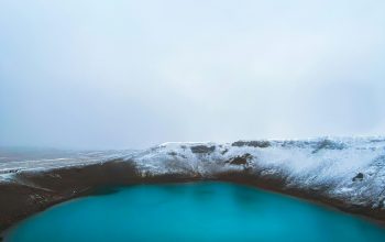 Wallpaper A Blue Lake Surrounded by Snow-Covered Hills