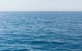 Wallpaper A Large Body of Water with a Boat in the Distance