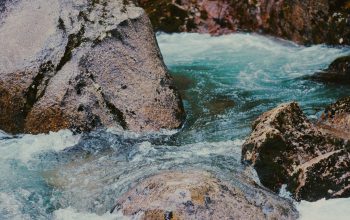 Wallpaper A Man Standing on a Rock Next to a River
