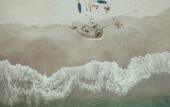 Wallpaper Aerial Photo of People Lying on Seashore Near Kayaks During Daytime
