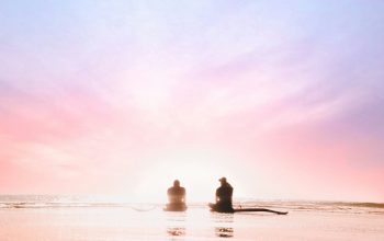 Wallpaper Silhouette of Two People Sitting on Seashore at Dawn