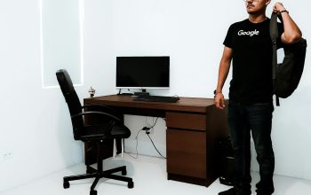 Wallpaper Man Standing Near Brown Desk Beside White Wall