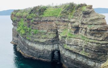 Wallpaper A Large Cliff with a Body of Water Below