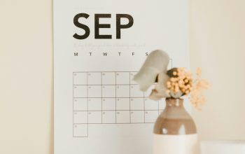 Wallpaper A Desk with a Calendar and a Vase of Flowers