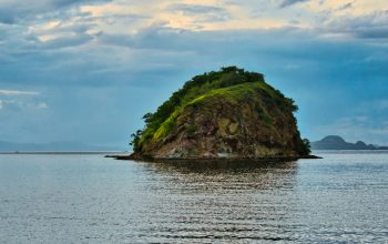 Wallpaper Green and Brown Rock Formation on Sea Under Blue Sky