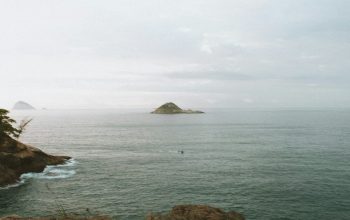 Wallpaper Brown Rock Formation on Sea Under White Sky During Daytime