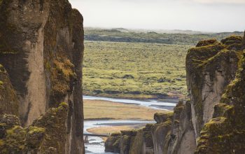 Wallpaper Person Standing on Rock Formation Near Body of Water During Daytime