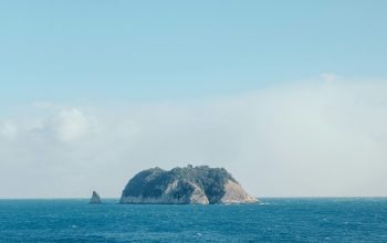 Wallpaper Black and Gray Rock Formation on Sea Under Blue Sky