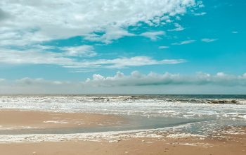 Wallpaper A Person Walking on a Beach with a Surfboard