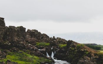 Wallpaper Green and Brown Rocky Mountain Beside River Under White Sky During Daytime