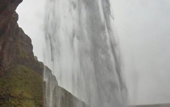 Wallpaper A Large Waterfall Pouring Water into a Body of Water