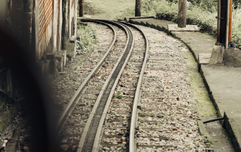 Wallpaper A Train Track with a Building in the Background